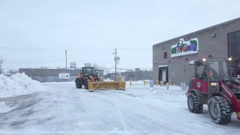 Snow Plows Clearing Nature Store Parking Lot on Snowy Winter Morning Stock Footage 230695183