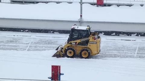 Snow removal with a skid steer on a rooftop parking area in winter weather in a Stock Footage 330156452