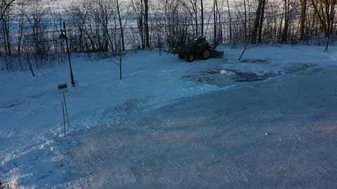 Snow removal tractor removing some snow near the frozen lake 動画素材 164251133