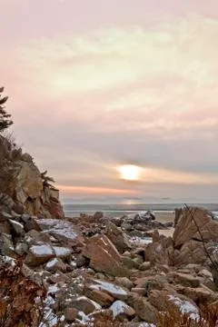 Snow on rocks_beach sunset Stock Photos