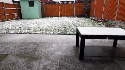 Snow, sleet rain falling and melting in suburban back garden Stock Footage 148037079