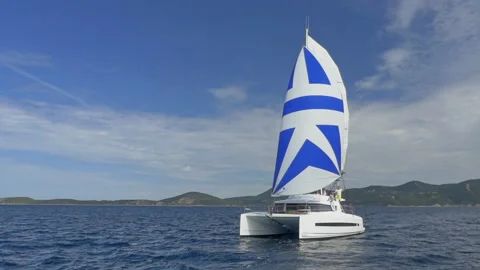 Snow-white sailing catamaran sails under full sail on blue sea against the Stock Footage 222956205