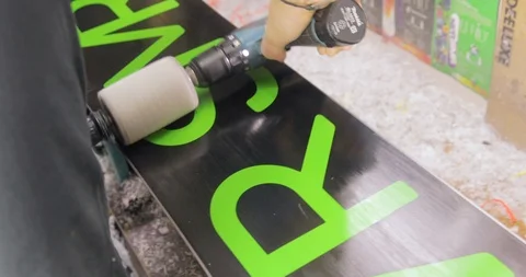 Snowboard Service. Motion Close Up Of A Machine Brushing A Waxed Board Stock Footage 125857248