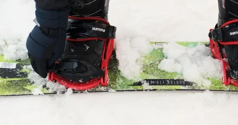 A snowboarder adjusts his bindings Stock Footage 124107597