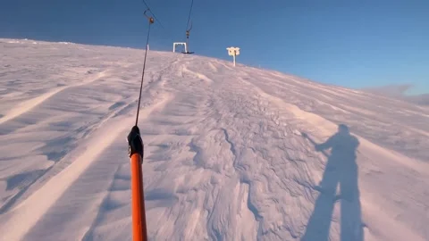 Snowboarder being pulled uphill by a t-bar drag lift at a ski resort 스톡 동영상 144790606