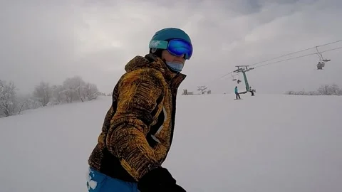 A snowboarder in bright clothes quickly descend from a snowy mountain Stock Footage 223570764