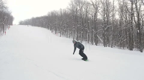 Snowboarder carves while snowboarding down a slope Vidéo 59711853