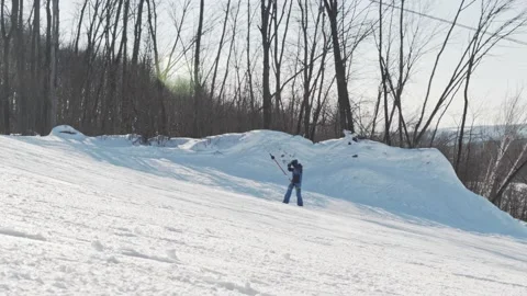 Snowboarder climbs up alone on a hill using a T-bar lift at a ski resort Stock Footage 221745519