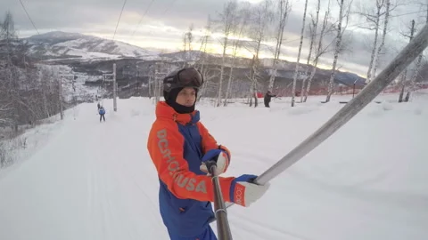 A snowboarder climbs the mountain using a lift. Ural mountains at sunset in the  Stock Footage 130746513
