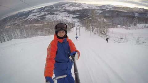 A snowboarder climbs the mountain using a lift. Ural mountains at sunset in the  Stock Footage 130746541