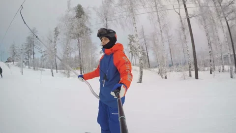 A snowboarder climbs the mountain using a lift. Ural mountains and winter forest Stock Footage 130746571