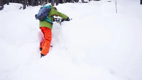 Snowboarder climbs on the slope to the trees Stock Footage 122867898
