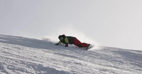 Snowboarder doing hand drag on fresh snow surface, snow spraying into the camera Stock Footage 254731770