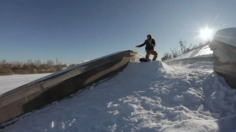 Snowboarder doing a slide trick on a ledge in the street Stock Footage 64508657
