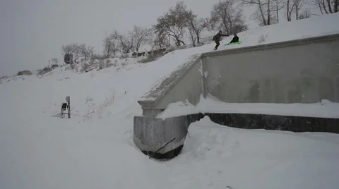 Snowboarder doing a trick on a ledge in the street Stock Footage 64508155