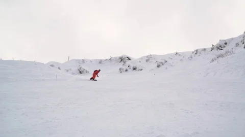 Snowboarder dressed up in bright clothes makes snow waves and throws snow on the Video stock 101788152