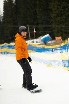 A snowboarder dressed in a bright orange jacket navigates a snowy slope, with Stock Photos