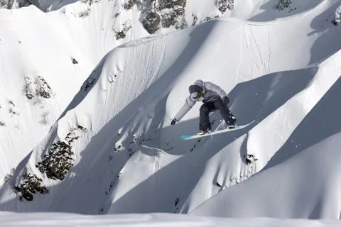Snowboarder flying on the background of snowy slope. Extreme winter sports Stock Photos