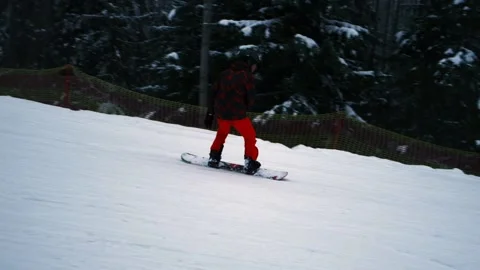 A snowboarder goes down a mountain Stock Footage 230879280