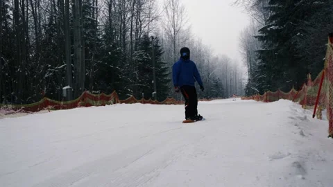 A snowboarder goes down a mountain, a guy goes snowboarding in a ski complex Stock Footage 230877888