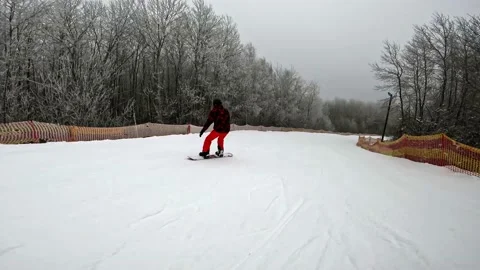 A snowboarder goes down a mountain, a guy goes snowboarding in a ski complex Stock Footage 230886967
