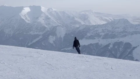 Snowboarder going down and mountains on background Stock Footage 103323843