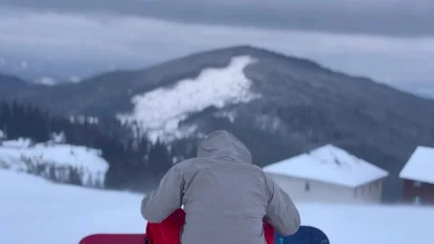 Snowboarder lying on snow and looking at mountains close-up Stock Footage 296116451