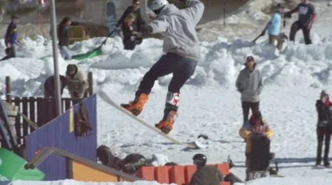 Snowboarder performs air transfer to frontside boardslide on rail Stock Footage 61627588
