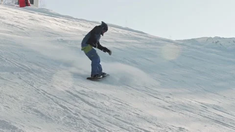 Snowboarder performs an ollie trick on a high speed and goes down the slope Stock-Footage 221581704