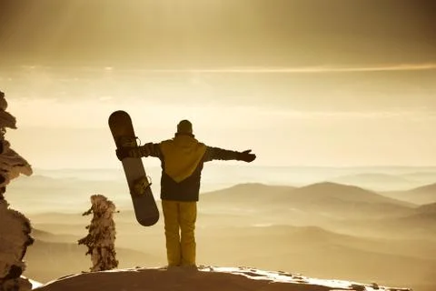Snowboarder posing on blue sky backdrop in mountains fog Stock Photos