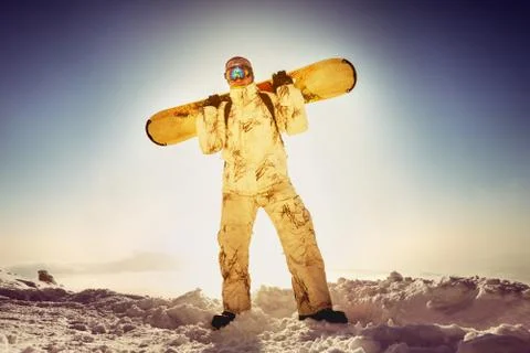 Snowboarder posing on blue sky backdrop in mountains Stock Photos