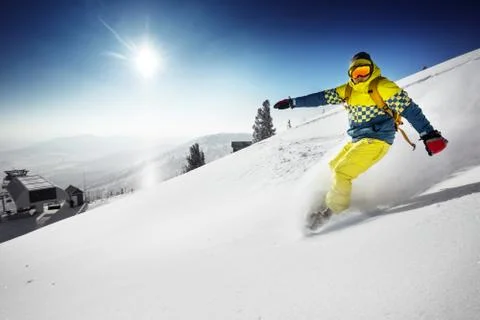 Snowboarder posing on blue sky backdrop in mountains 스톡 사진