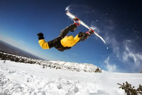 Snowboarder posing on blue sky backdrop in mountains Stock-Fotos