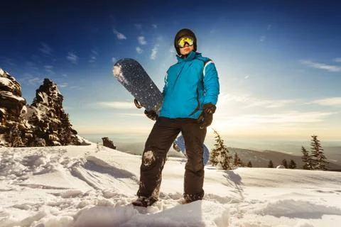 Snowboarder posing on blue sky backdrop in mountains Stock Photos