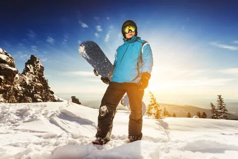 Snowboarder posing on blue sky backdrop in mountains Stock Photos