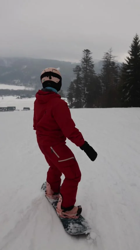 Snowboarder in red outfit rides downhill on snowy slope at mountain resort Stock Footage 327092353