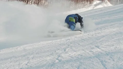 A snowboarder rides down from hill, makes several tricks and falls at high speed Stock-Footage 221745593