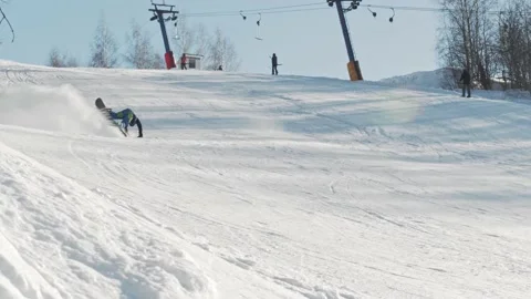 A snowboarder rides down a slope, performs a tripod trick and falls on the slope Video stock 221745336