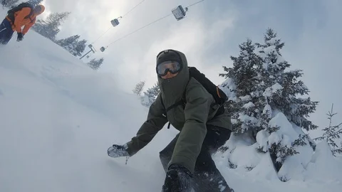A snowboarder rides through snow on a steep hill and does quick turns in powder. Stock Footage 107459800