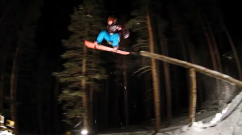 Snowboarder rides off tree jump Stock Footage 37624265