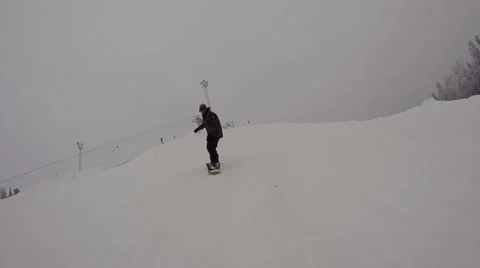 Snowboarder riding down and jumping from kicker Stock Footage 64508994