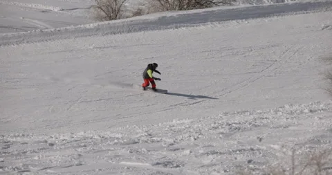 Snowboarder riding downhill fast, doing hand drag. Snowboarder riding in the Stock Footage 255879077