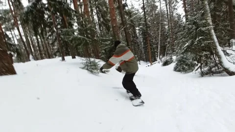A snowboarder is riding through the plump snow in the forest between the trees Stock Footage 262573465