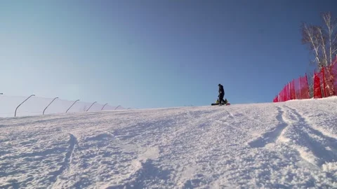 The snowboarder rolls down the ski slope and brakes sharply. Stock Footage 256156323