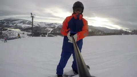 A snowboarder shows a sunset while descending a mountain Stock Footage 130746832