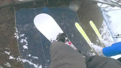 Snowboarder with skier going down from ski lift Stock Footage 151045381