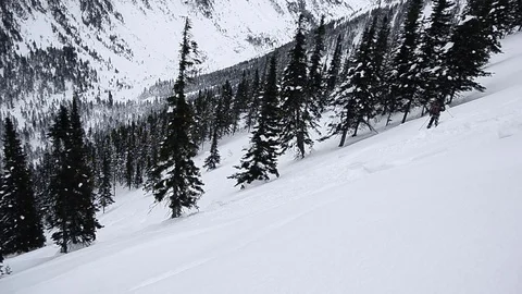 Snowboarder sliding down snow covered mountain at ski resort Stock Footage