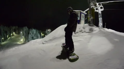 Snowboarder starts to move down the mountain at night Stock Footage 64508877