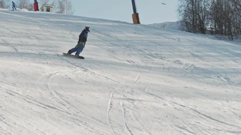 Snowboarder technically carves down the hill and performs an indie grab trick Stock Footage 162269430
