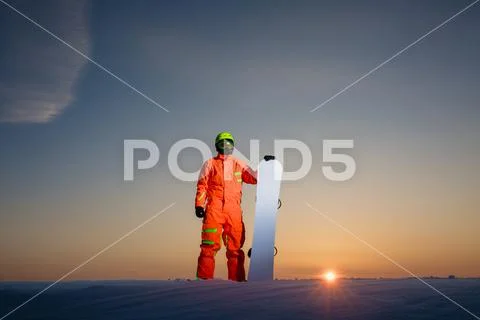 Snowboarder on the top of the ski slope at the background of beautiful sunset Stock Photos